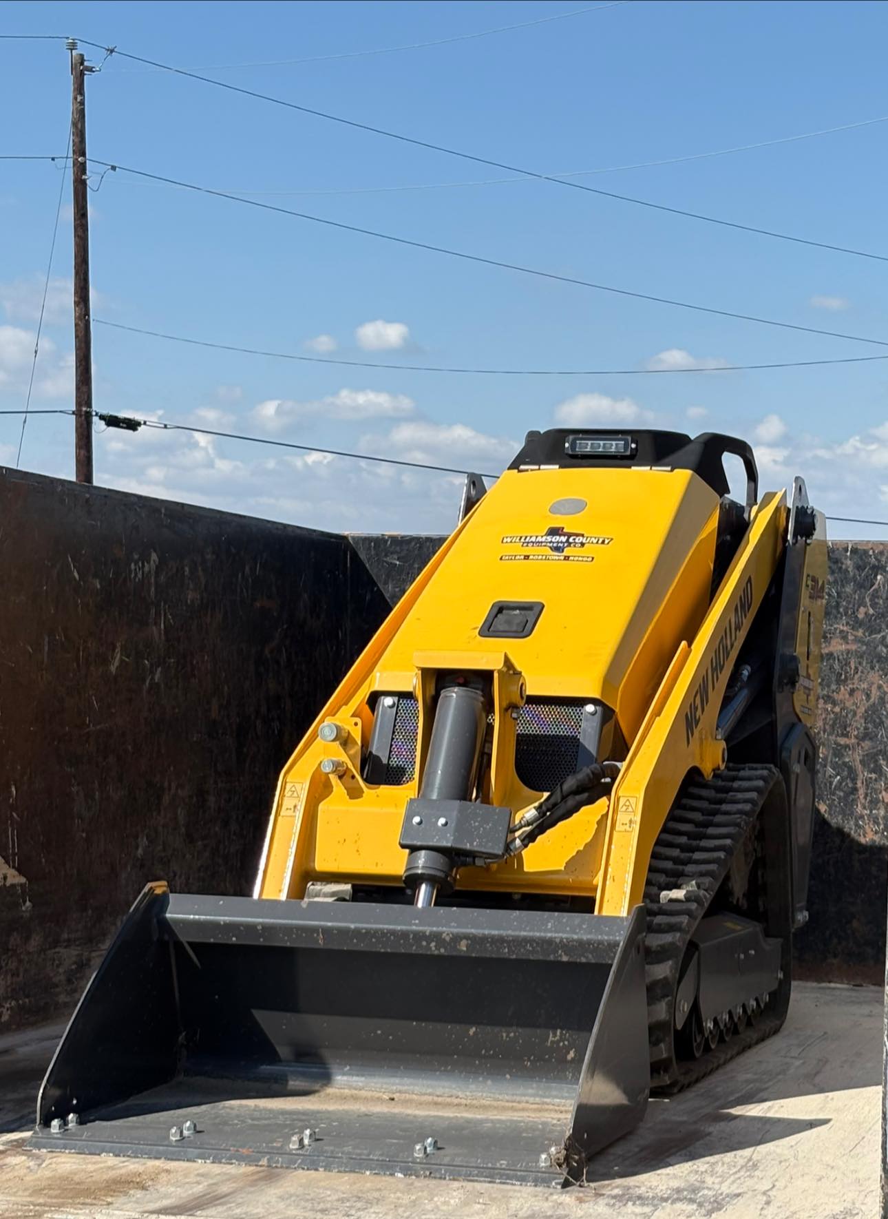 New Holland skid steer loaded inside dump container
